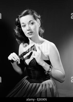 Modell mit Ventilator im trägerlosen Kleid. Modell mit Ventilator im trägerlosen Kleid. c.1964 Stockfoto