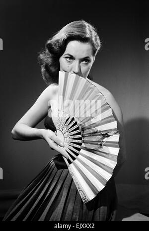 Modell mit Ventilator im trägerlosen Kleid. Modell mit Ventilator im trägerlosen Kleid. c.1964 Stockfoto