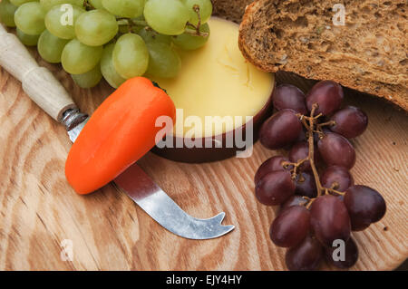 Käse, Brot und Trauben auf Holz Schneidebrett Stockfoto