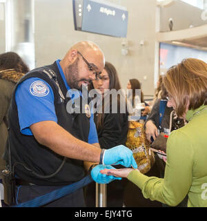 Romulus, Michigan - A Transportation Security Administration Officer Tupfer des Passagiers Hand für Spuren von Sprengstoff. Stockfoto