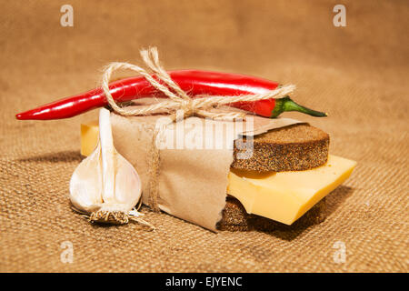 Sandwich mit Käse eingewickelt in Papier, Chilischote und Knoblauch auf alten Tuch Stockfoto