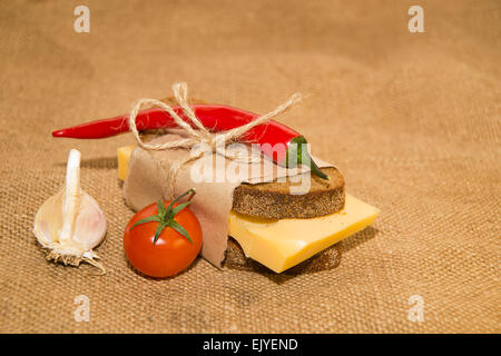 Sandwich mit Käse eingewickelt in Papier, Cherry-Tomaten und Knoblauch auf alten Tuch Stockfoto
