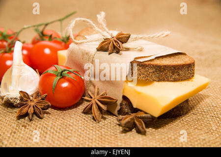 Sandwich mit Käse eingewickelt in Papier, Cherry-Tomaten und Knoblauch auf Tuch Stockfoto