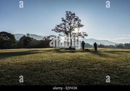 Fotografen, die Silhouette gegen die Morgensonne vor einen Baum auf einer Wiese in Nara, Japan Stockfoto