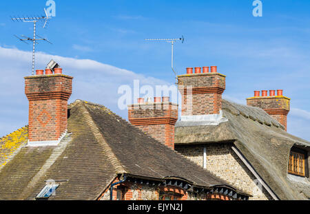 Red brick Schornsteine auf Stroh und Dächer in England, Großbritannien. Stockfoto