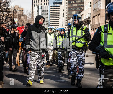 MONTREAL, KANADA, 2. APRIL 2015. Aufruhr in den Straßen von Montreal gegen die wirtschaftlichen Sparmaßnahmen. Polizist und Mobilfunktarife Stockfoto