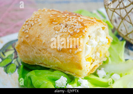 Stück hausgemachter Käsekuchen mit grünem Salat auf einem dekorierten Tablett Stockfoto