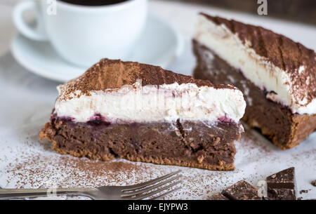 Schokoladenkuchen mit Schlagsahne, bestäubt mit Kakao und Kaffee hautnah Stockfoto