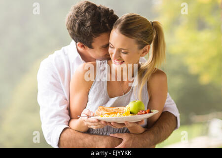 verspielte junge Mann umarmt Freundin während der Frühstückszeit am Morgen Stockfoto