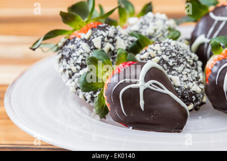 Hand Erdbeeren in Schokolade getaucht, mit einigen rollte in gerösteten Cashew-Kerne und einige mit einem weißen Schokolade Nieselregen Stockfoto