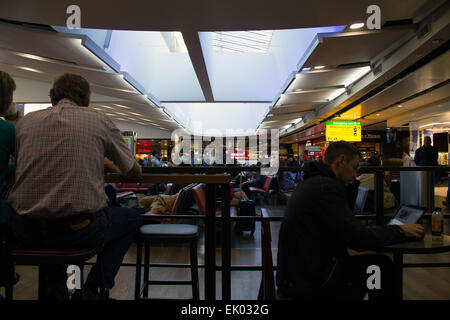 Ein Großteil der Passagiere in einem Wartebereich mit Food Court und Geschäfte in London Heathrow International Airport Stockfoto