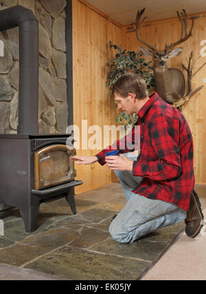 Schöner Mann, der sich die Hände in der Nähe des Holzofens wärmte Stockfoto