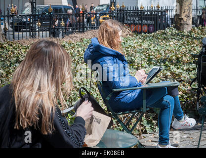 Eine Frau benutzt ihr iPad verbinden andere Besucher der Park das Vergießen der Winterdepression im Bryant Park in New York auf Donnerstag, 2. April 2015. Warmen Wetter in der Mitte der 60er Jahre zog Büroangestellte und Touristen im Freien. (© Richard B. Levine) Stockfoto