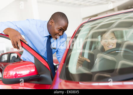 schönen afrikanischen Verkäufer erklären Auto Funktionen mit potenziellen Kunden Stockfoto