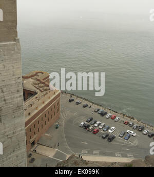 Grauen Himmelsblick auf Advektion Nebel über der Bucht von San Francisco von Fort Point unterhalb Süden Abutment Pylon, Golden Gate Bridge geparkten Autos Stockfoto