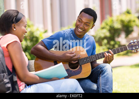 romantische junge afrikanische Studentin Gitarre für seine Freundin auf dem campus Stockfoto