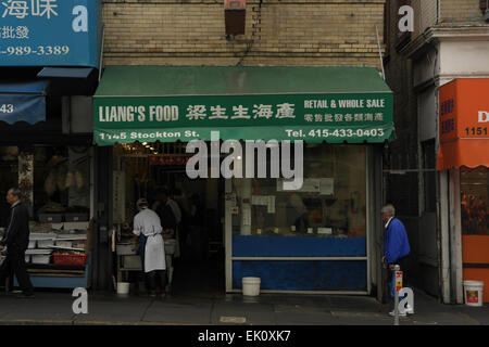 Ansicht-Männer gehen Bürgersteig letzten weiße Overalls Arbeiter, Liangs Meeresfrüchte Shop, Stockton Street, Chinatown, San Francisco, USA Stockfoto