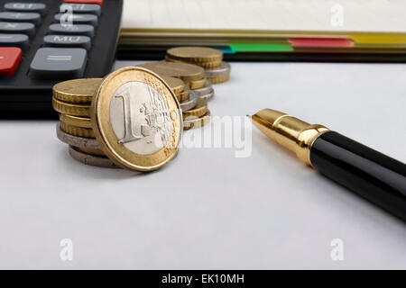 Euro (EUR)-Münzen, Notebook, einen Taschenrechner und einen Stift mit einer 1 Euro Münze vor. Stockfoto