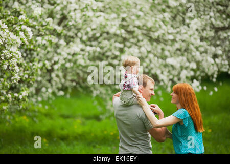 Glückliche Familie Spaß im Freien im Frühlingsgarten. Vater, Mutter und Kind. Familienkonzept Stockfoto