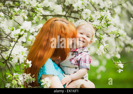 Porträt von glücklich glückliche Mutter und Sohn im Frühlingsgarten. Sie spielen und lachen. Blühende Apfelbäume. Familien-Konzept. Stockfoto