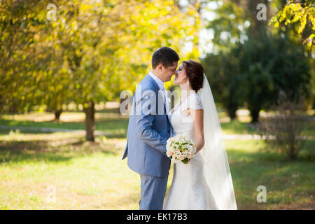 glückliche Braut, Bräutigam stehen im grünen Park, küssen, Lächeln, lachen, umarmen. Liebhaber in Hochzeitstag Stockfoto
