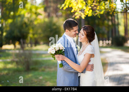 glückliche Braut, Bräutigam stehen im grünen Park, küssen, Lächeln, lachen, umarmen. Liebhaber in Hochzeitstag Stockfoto