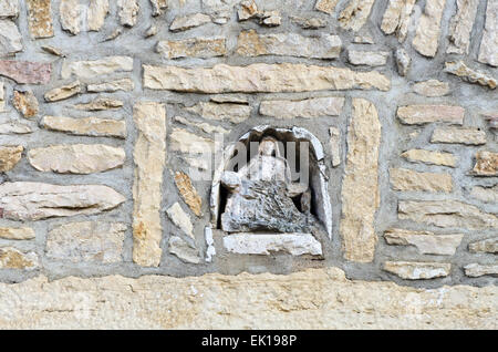 Eine kleine Statue von der Piéta ist in eine Nische in einem Steingebäude mit Blick auf den Place du Jet d ' eau, Santenay, Frankreich versteckt. Stockfoto