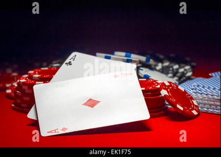 zwei Asse und ein Haufen von Poker-Chips auf einem roten Tisch Stockfoto