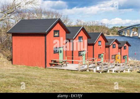 SENOREN, Schweden - 3. April 2015: Fünf roten Hütten am Hang in Richtung Meer mit einer Brücke im Hintergrund. Gesicht des weiblichen sunb Stockfoto