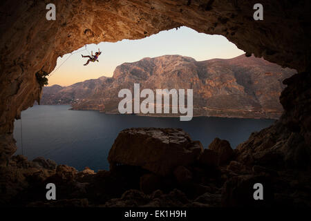 Weibliche Kletterer fallen von einer Klippe in einer großen Höhle auf Kalymnos, Griechenland Stockfoto