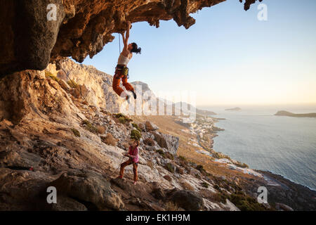 Junge Frau im Schwierigkeitsklettern auf überhängenden Felsen, weiblichen Partner sichern Stockfoto