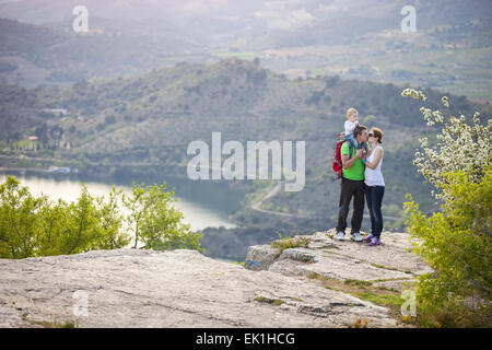 Junges Paar mit Kleinkind Jungen stehen auf Felsen und küssen Stockfoto