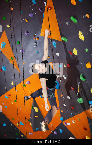 Junger Mann üben Klettern in der Kletterhalle im Innenbereich Stockfoto
