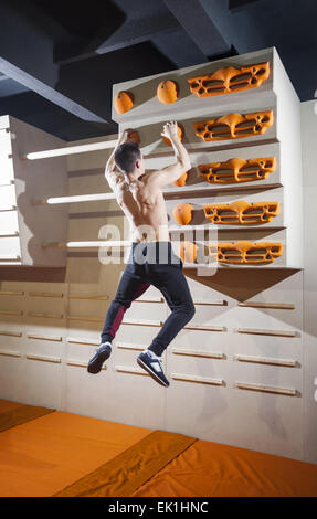Junger Mann üben Klettern in der Kletterhalle im Innenbereich Stockfoto