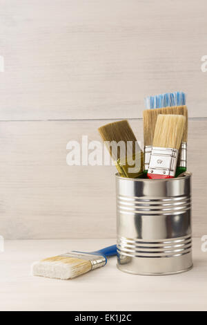 Farbeimer und Pinsel auf hölzernen Hintergrund Stockfoto