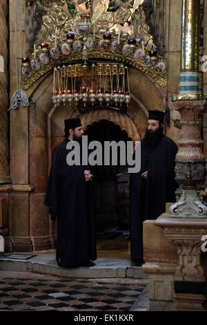 Griechisch-orthodoxe Geistliche stehen am Eingang der Rotunde Edicule oder Anastasia, die die Engelskapelle enthält, eine Vorkammer, die zum Grab Jesu Christi führt, in der Kirche des Heiligen Grabes in der Altstadt von Jerusalem, Israel. Stockfoto