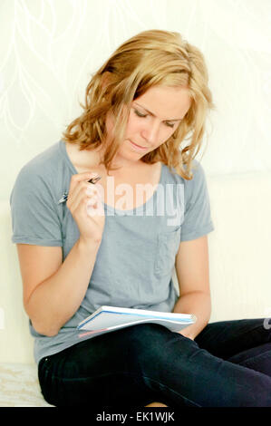 Junge Frau denkt über Notizen im Notizbuch Stockfoto