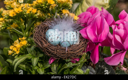 Flachen Fokus auf Ostereier in einem gefiederten Nest, umgeben von einem Blumen-Arrangement. Stockfoto