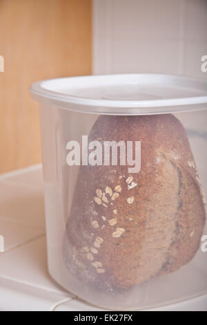 Frisch gebackene Vollkorn Brot gespeichert in Kunststoff-Container auf einer Kachel-Theke Stockfoto