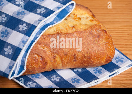 Drei-Käse-Brot, teilweise durch eine Serviette blau karierte Tuch eingewickelt Stockfoto