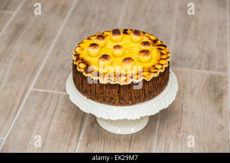 Traditionelle runde hausgemachte Simnel Kuchen auf einem weißen porzellan Kuchenständer für Ostern - Obstkuchen mit geröstetem Marzipan Topping und Bälle Stockfoto