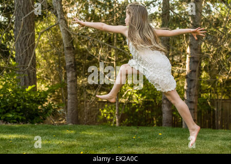 Sieben Jahre altes Mädchen springen in der Luft in ihrem Hinterhof in Issaquah, Washington, USA Stockfoto