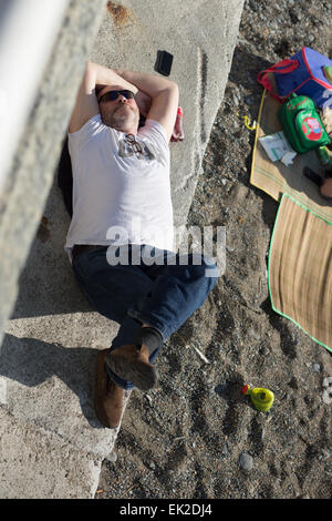 Aberystwyth, Wales, UK. 5. April 2015. Ostersonntag. Das Wetter. Ein Mann, Sonnenbaden am Meer Betonwand neben dem Strand. Bildnachweis: Alan Hale/Alamy Live-Nachrichten Stockfoto