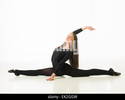 wunderschönen Ballett-Tänzerin, die Durchführung einer Spaltung auf Studioboden auf weißem Hintergrund Stockfoto