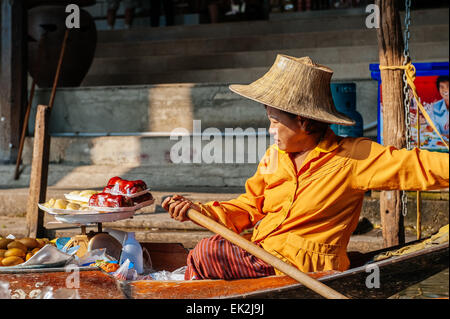 Thai Frau verkauft Obst von einem Boot auf dem schwimmenden Markt in Damnoen Saduak. Der schwimmende Markt ist eine wichtige touristische Attraktion. Stockfoto