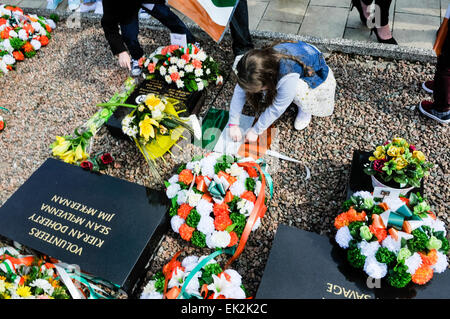 Ein junges Mädchen legt einen Kranz am IRA republikanischen Grundstück in Milltown Friedhof, Belfast Stockfoto