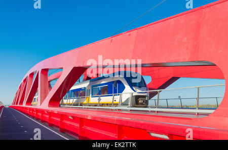 Zug vorbei die neue rote Eisenbahnbrücke über die IJssel in den Niederlanden Stockfoto