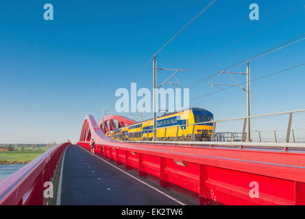 Zug vorbei die neue rote Eisenbahnbrücke über die IJssel in den Niederlanden Stockfoto