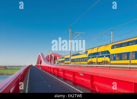 Zug vorbei die neue rote Eisenbahnbrücke über die IJssel in den Niederlanden Stockfoto