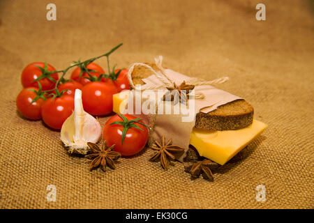 Sandwich mit Käse eingewickelt in Papier, Cherry-Tomaten und Knoblauch auf alten Tuch Stockfoto